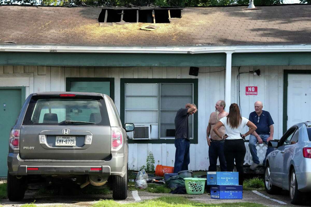 Neighbors stand around a multi-room renting facility in the aftermath of a shooting that left four people dead Sunday, Aug. 28, 2022 in Houston. A longtime tenant facing eviction started several fires early Sunday in southwest Houston and then shot at residents as they fled the blaze, killing three before authorities fatally shot him, police said