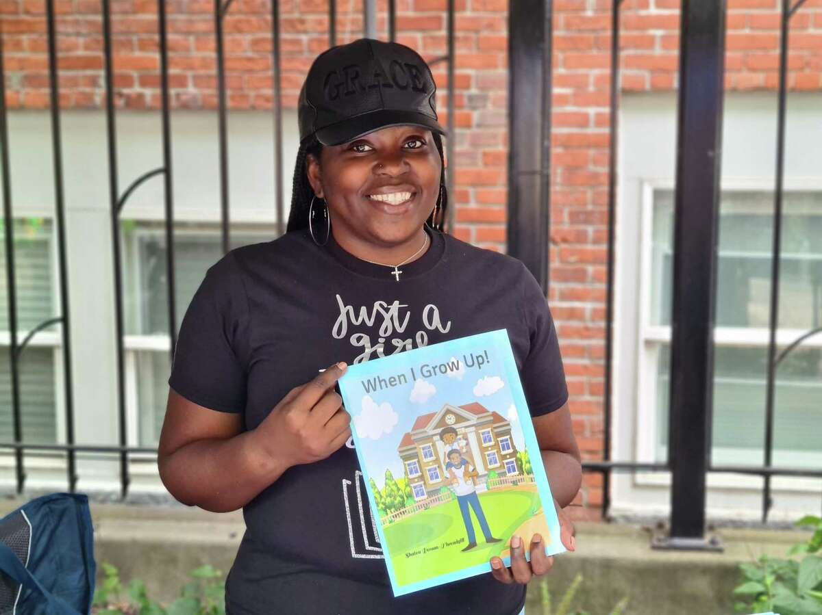 Shatea Person poses with her first children’s book, “When I Grow Up!,” at Black Wall Street Festival at Temple Plaza in New Haven Aug. 27, 2022.