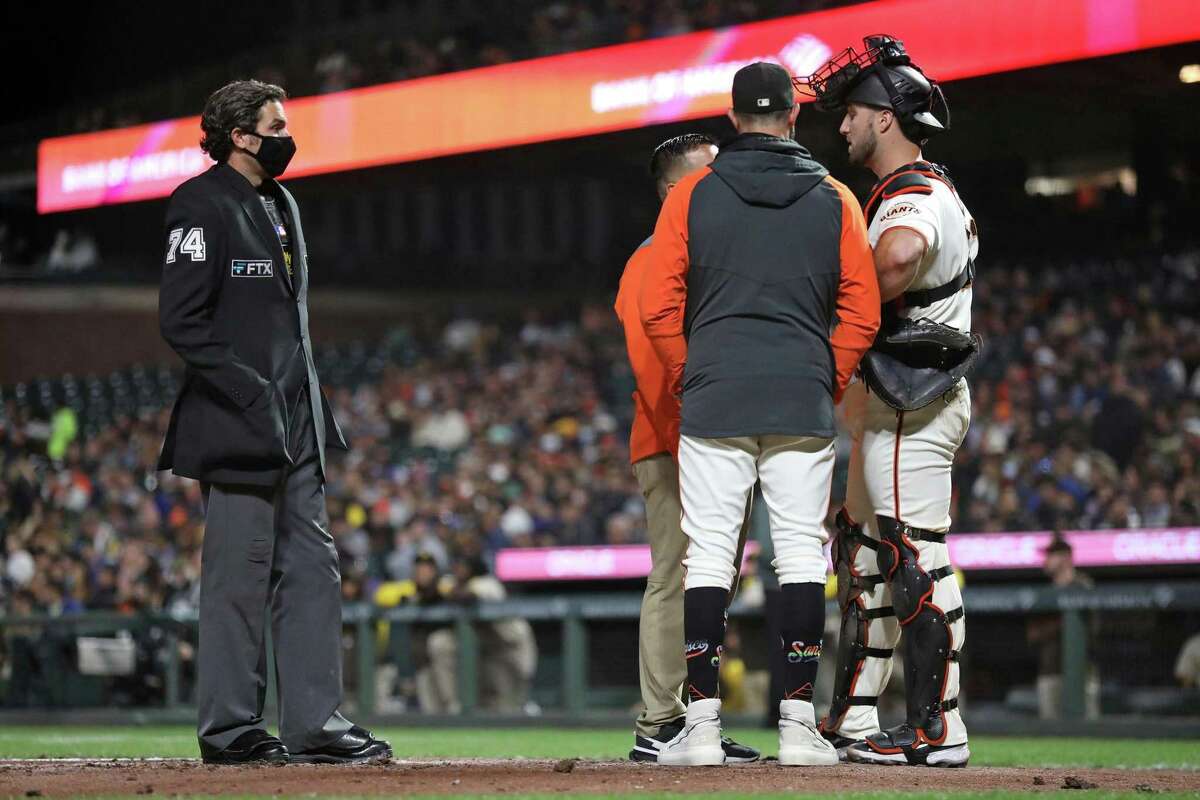 San Francisco Giants’ Joey Bart is checked by manager Gabe Kapler and a trainer after Bart was injured against San Diego Padres during MLB game at Oracle Park in San Francisco, Calif., on Monday, August 29, 2022.
