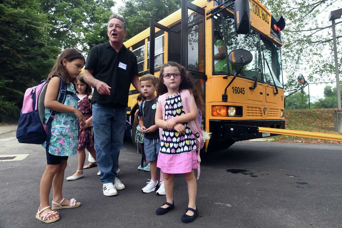 Lee Mansy, a paraprofessional, helps direct students as they arrive by bus for the first day of school at Coleytown Elementary School, in Westport, Conn. Aug. 30, 2022.