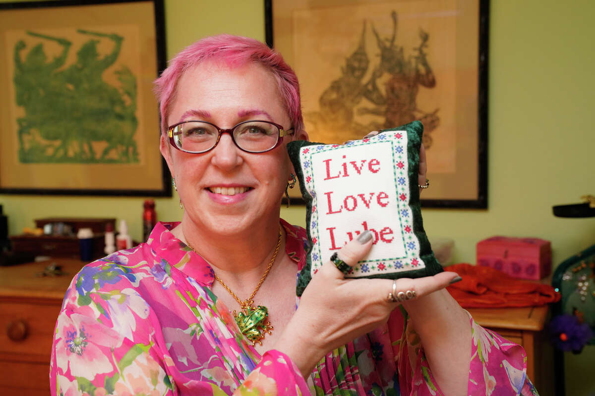 Wendy Moreland holds a pillow with a cheeky twist on the home decor motto, "Live love laugh." The San Antonio knitting instructor also does her share of NSFW cross stitch and knitting designs.