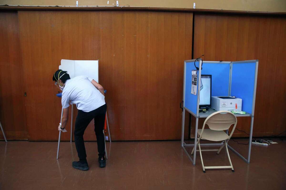 A poll worker sanitizes a voting booth at the Lakeside Park Garden Center in Oakland, Calif. on Nov. 3, 2020.