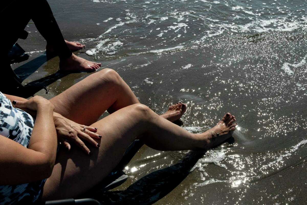 Catherine Reese of Vancouver, Washington dips her toes in the waves while sitting on beach chairs at Stinson Beach in Stinson Beach, Calif. Friday, October 16, 2020. Temperatures across the Bay Area reached record highs this week, drawing inland residents to the coasts to beat the heat.