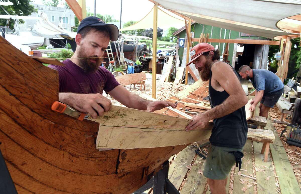 Tucker Yaro, left, and Anthony Daniels, center, of Leetes Island Boatworks attach a pattern to a replica of a Danish fishing vessel dating from 1130 in Stony Creek on August 23.
