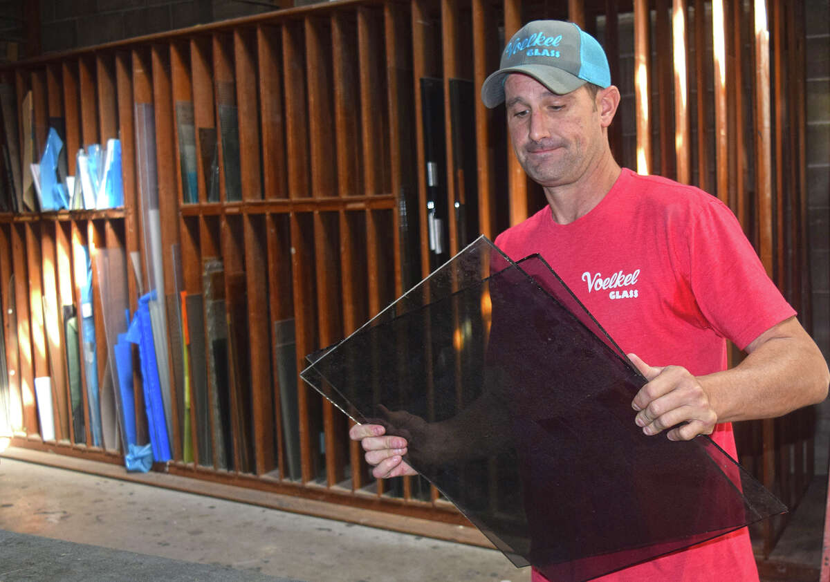 Voelkel Glass Service owner Drew Wagner carries off a cut pane of glass for disposal. The glassworks shop closed Wednesday.