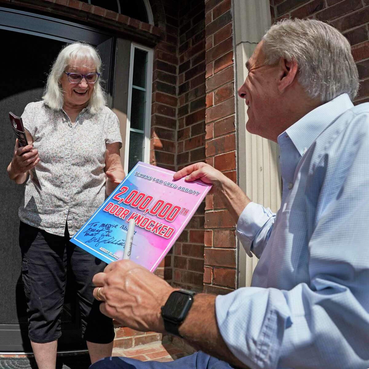 Texas Governor Greg Abbott talks with suburban Allen, Texas resident Maggie Pitka during a photo opportunity heralding the ceremonial ‘knock’ on the 2,000,000th door of the election cycle. CREDIT: Louis DeLuca for The Houston Chronicle
