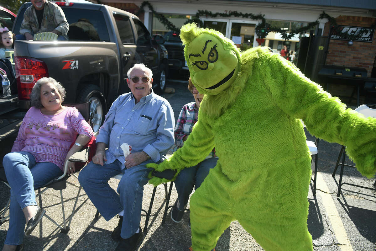The Grinch entertains the crowd, including Kim Smith, from left, and her parents Herman and Emily McClinton of Tomball during the 56th Annual Tomball Holiday Parade which featured about 150 entries marching, performing and driving down Main Street on Saturday, Nov. 20, 2021.