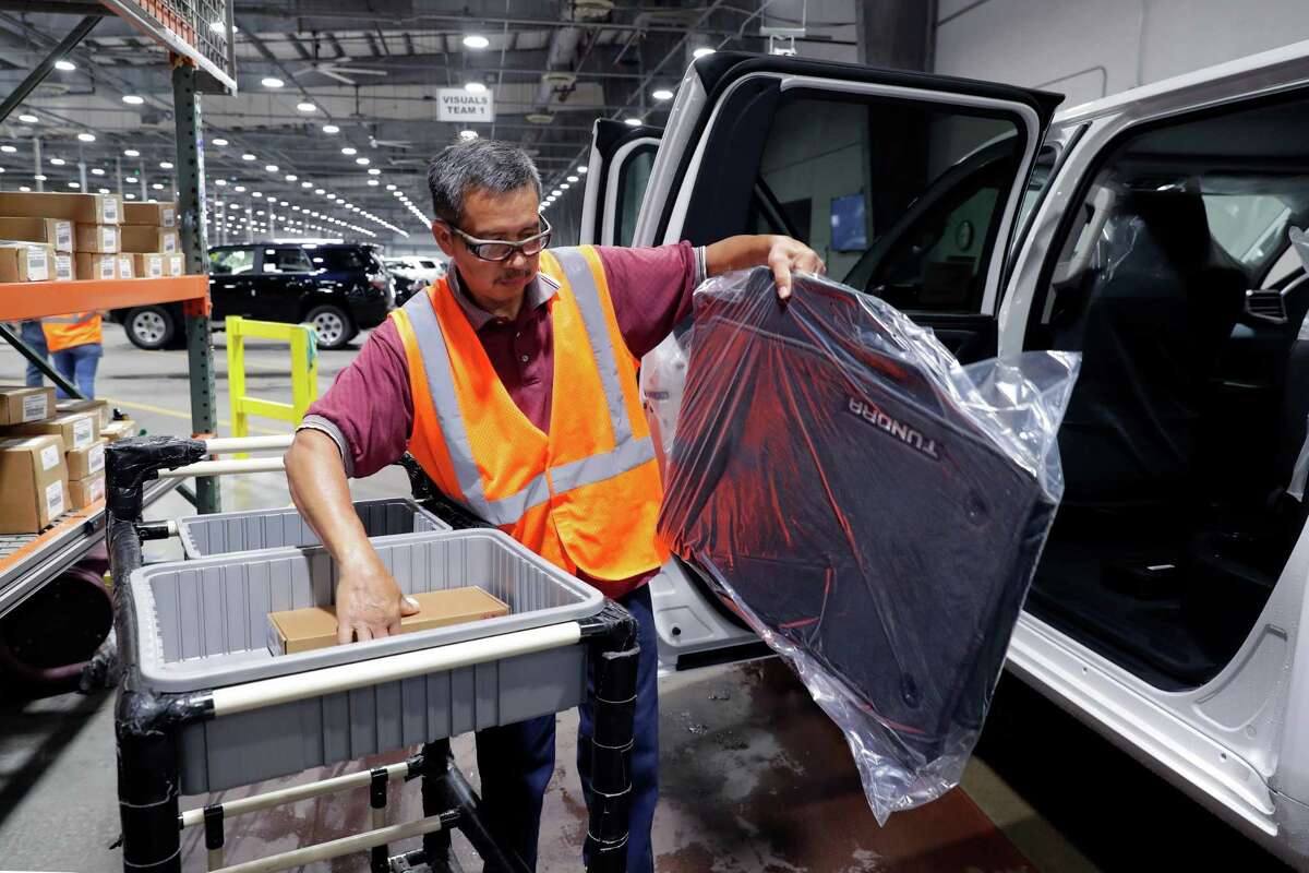 Sam Reyes installs floor mats and other accessories into a Toyota Tundra truck as it goes through processing before being shipped to dealerships at the Friedkin Group Gulf States Toyota processing facility Thursday, May 26, 2022 in Houston, TX.
