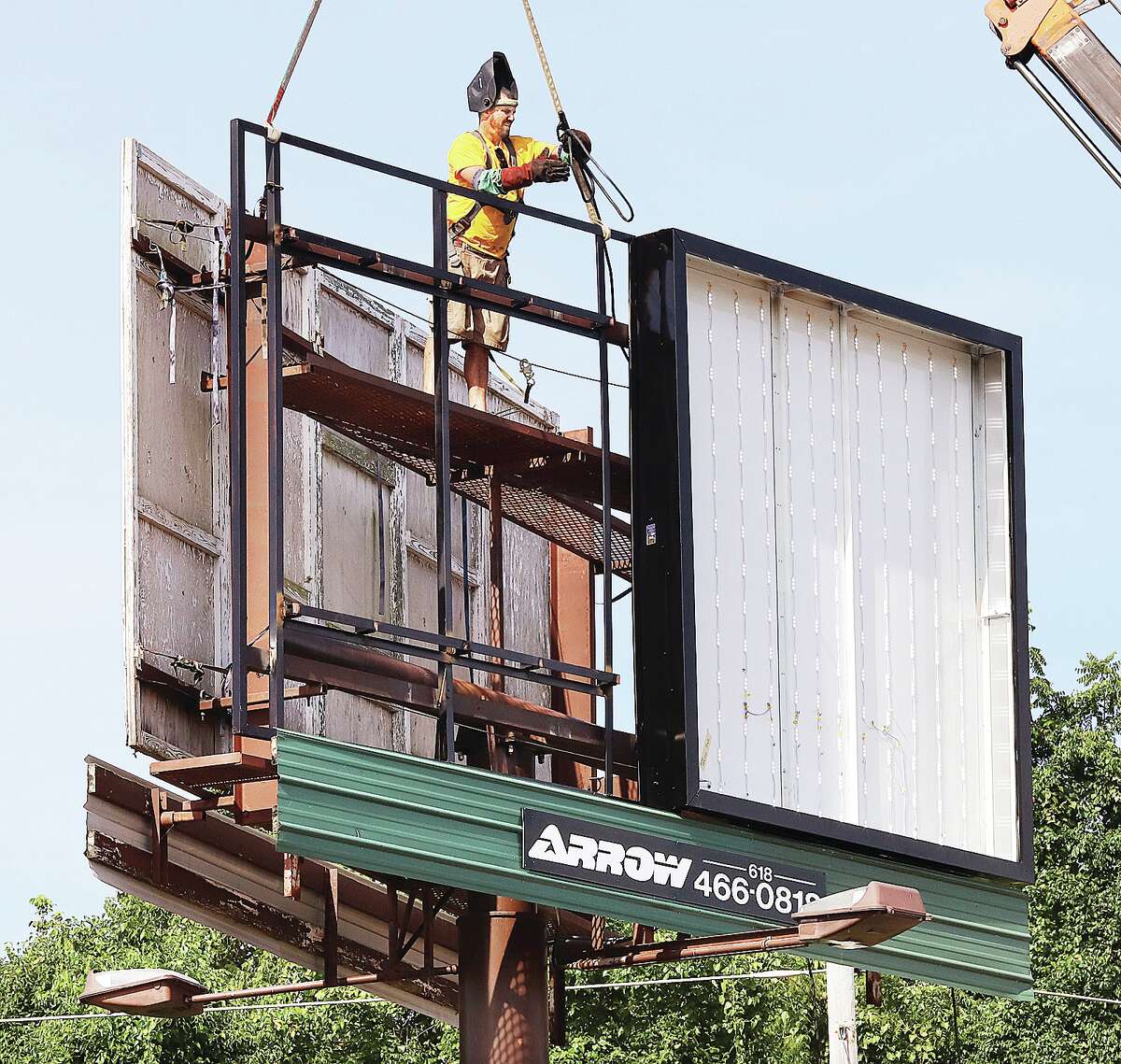John Badman|The Telegraph It was out with the old and in with the new Thursday as workers from Arrow Signs and Outdoor Advertising were fitting a traditional billboard with modern LED lights in the 100 block of Alton Square Mall Drive in Alton.