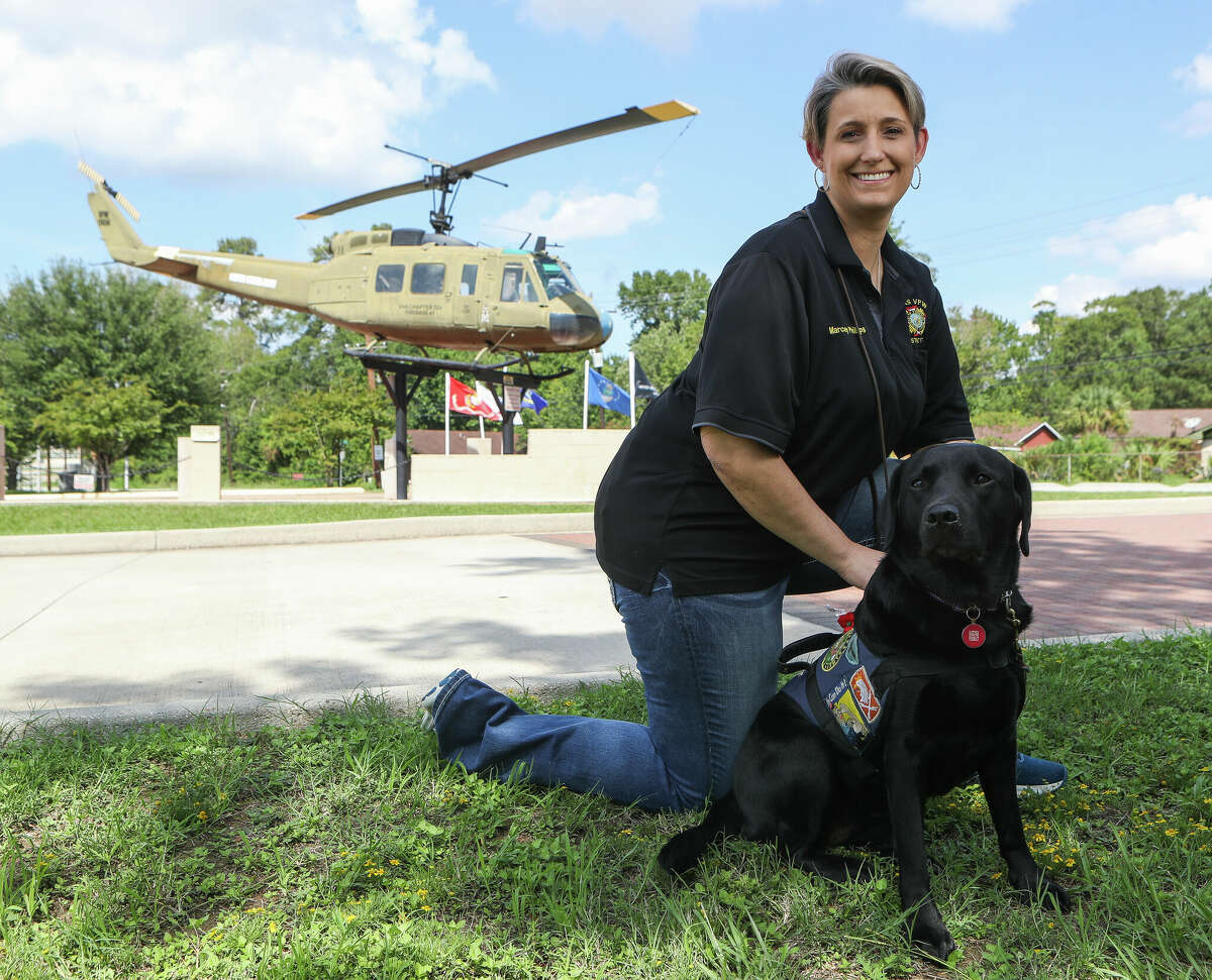 U.S. Army veteran Marcey Phillips poses for a portrait alongside her service dog, Beignet, outside the Conroe Veterans of Foreign Wars Post 4709, Thursday, Sept. 1, 2022, in Conroe. Phillips was recently honored for her dedication to her country and community by the VFWâs #StillServing campaign, which recognizes veterans who continue to serve in the community after the military. Phillips developed epilepsy during her time serving in the Iraq War and got her America black labrador two years ago to help wake Phillips from nightmares, deal with crowds or help detect seizures. Phillips said she is #StillServing because âit is heartwarming to see people change their understanding of service dogs and I love seeing the faces of veterans, kids and the elderly light up when Beignet and I visit.â