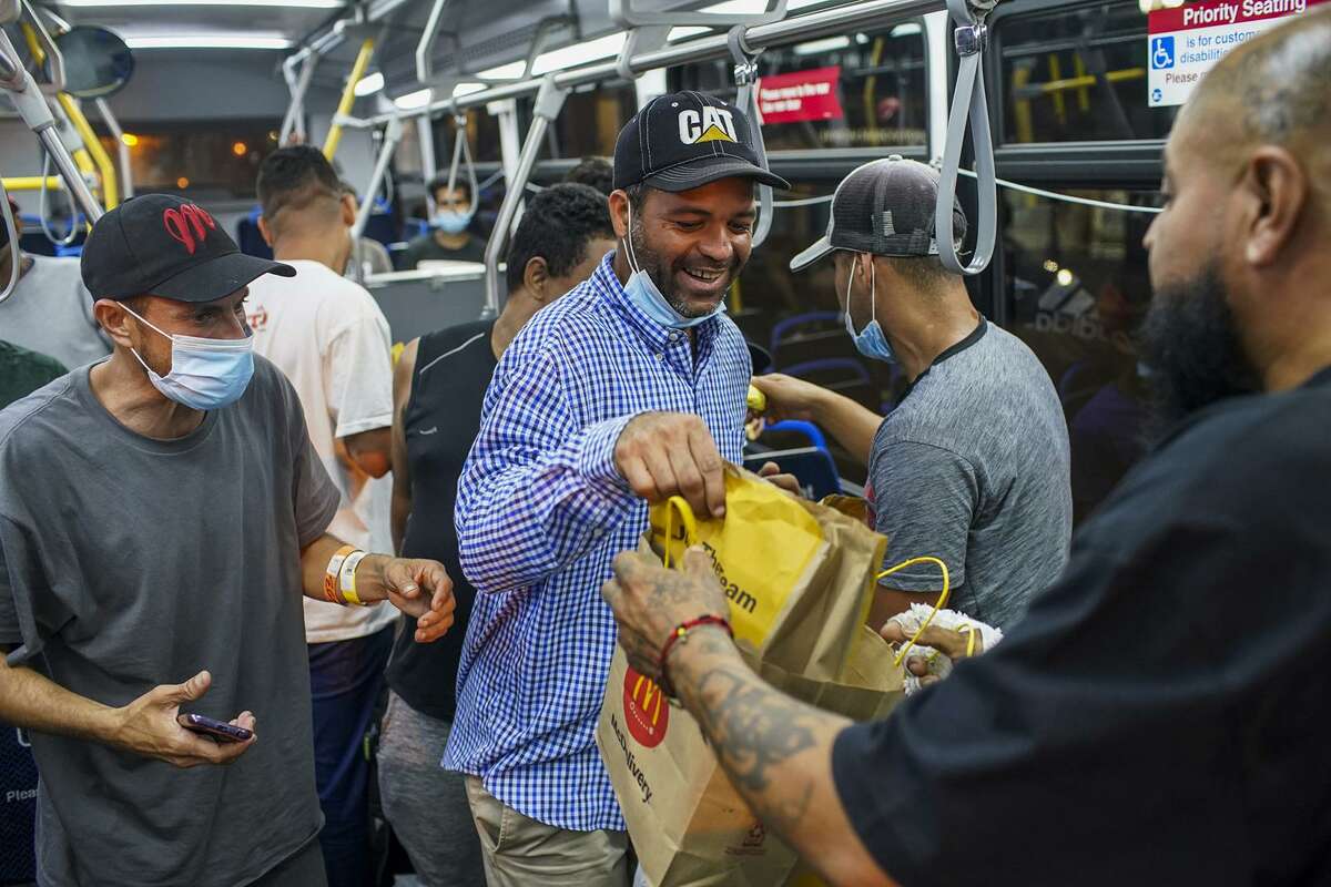 A group of migrants who arrived on a bus from Texas are given cheeseburgers as they prepare to take a CTA bus to a Salvation Army shelter on Aug. 31, 2022, in Chicago. The people, who had immigrated to Texas from other countries, were sent by bus by Texas Gov. Greg Abbott. (Armando L. Sanchez/Chicago Tribune/TNS)