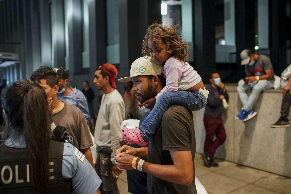 Elier Salazar Chacon, 29, carries his 3-year-old daughter Cataleya Salazar Ramirez while talking with a Chicago police officer after arriving on a bus with other migrants from Texas at Union Station on Aug. 31, 2022, in Chicago. (Armando L. Sanchez/Chicago Tribune/TNS)