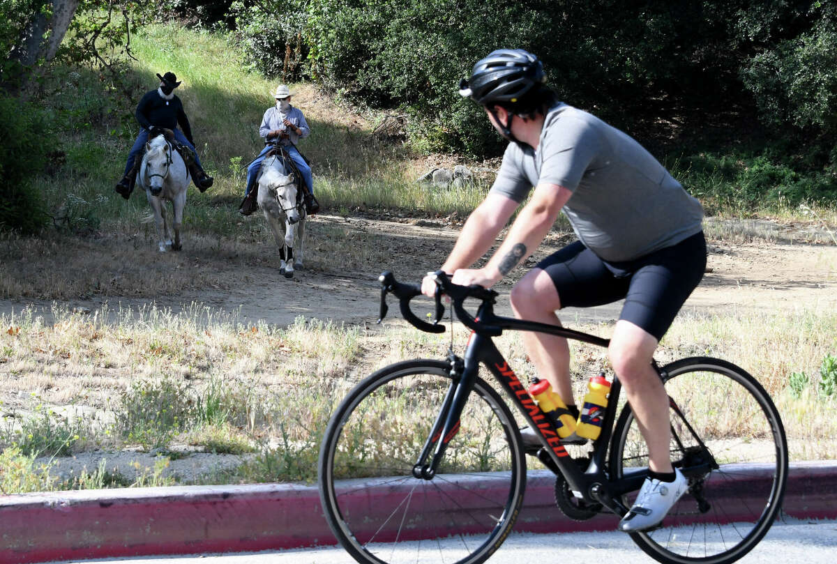 A cyclist overlooks equestrians on the trail.