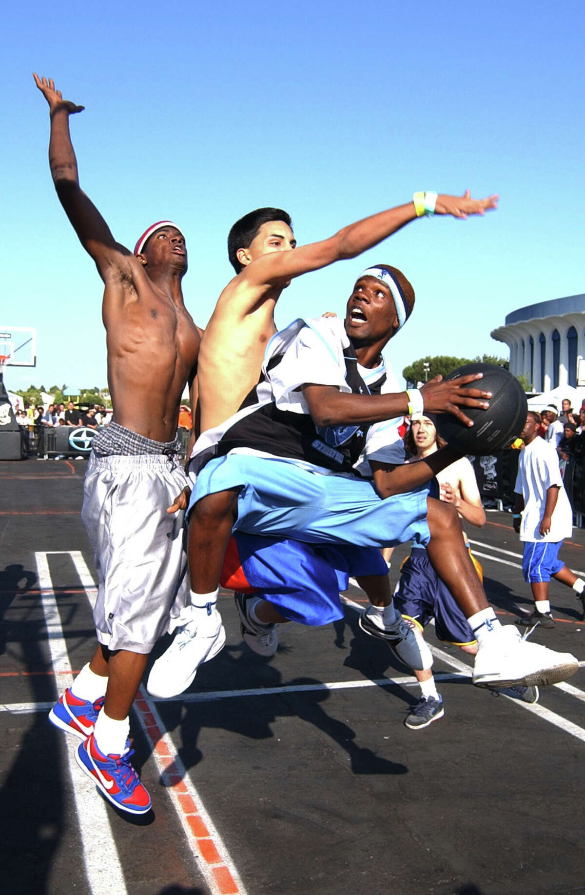 Les joueurs de streetball de Los Angeles se disputent la chance de jouer contre l'équipe AND1 2004 sur le toit noir du Great Western Forum à Inglewood, en Californie, le 9 juin 2004.