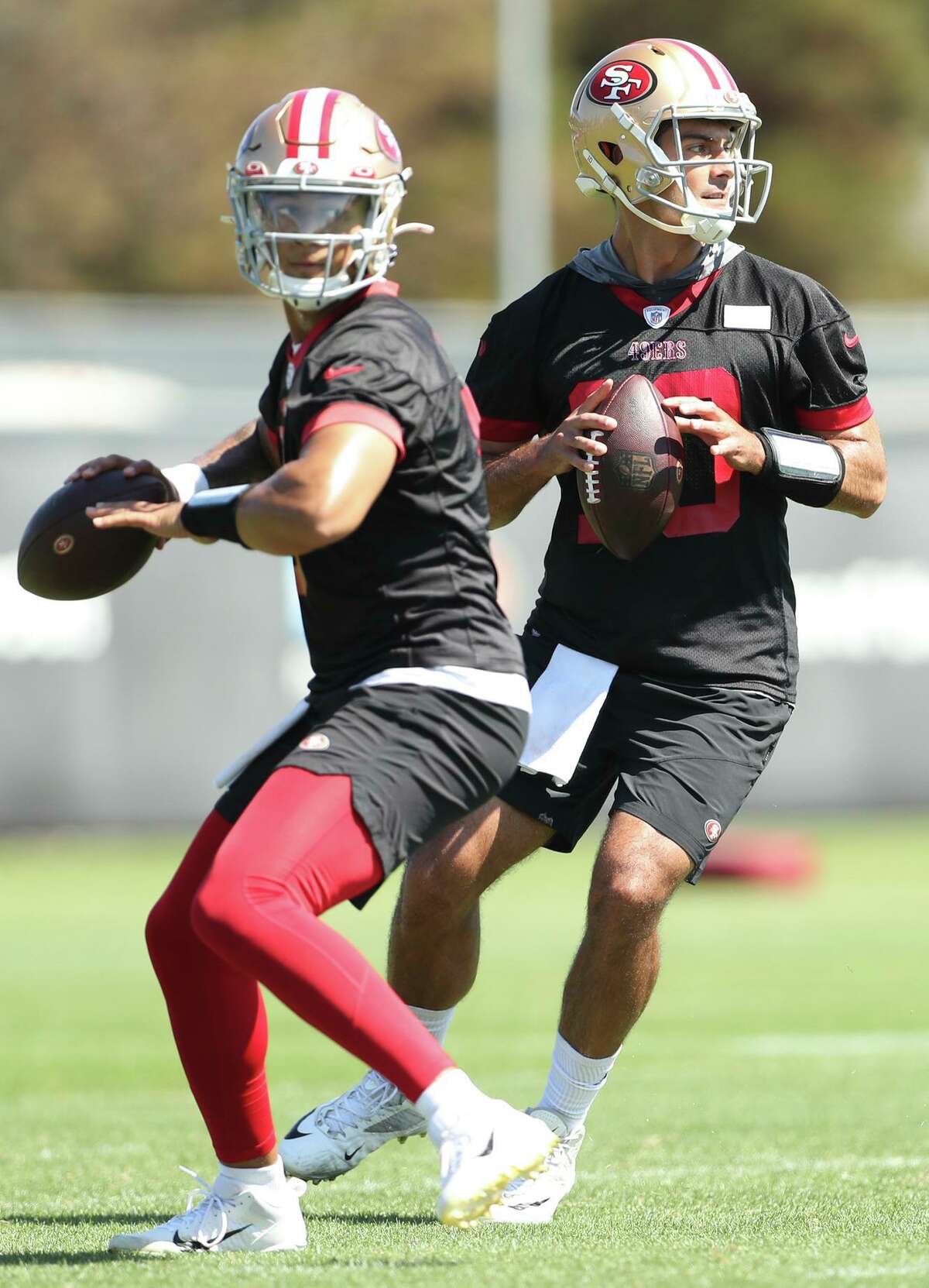 Current San Francisco starting quarterback Trey Lance (left) and backup Jimmy Garoppolo prepare to throw during practice Thursday in Santa Clara.