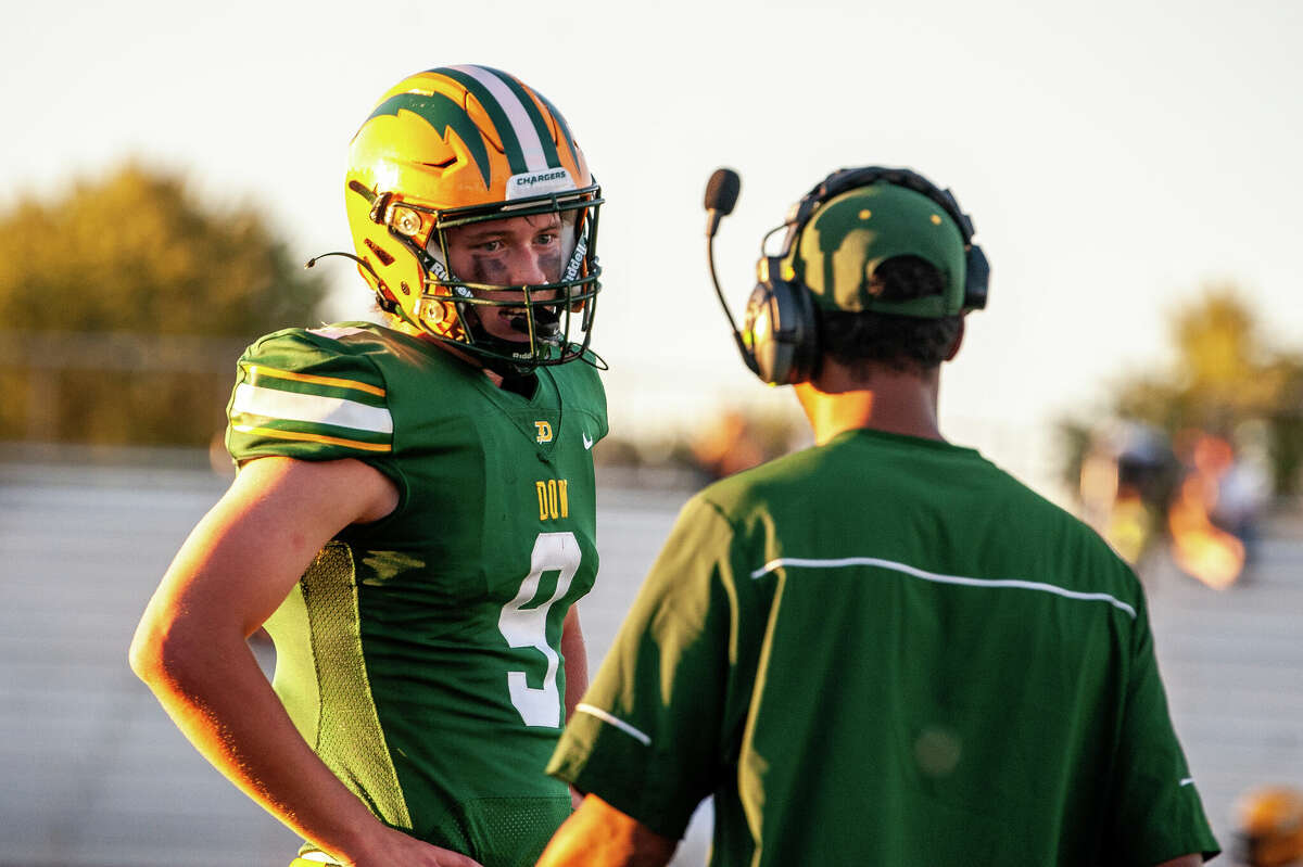 Dow High quarterback Jack Bakus talks with Chargers' coach Matt Peterson during Thursday's game against Saginaw United, Sept. 1, 2022.