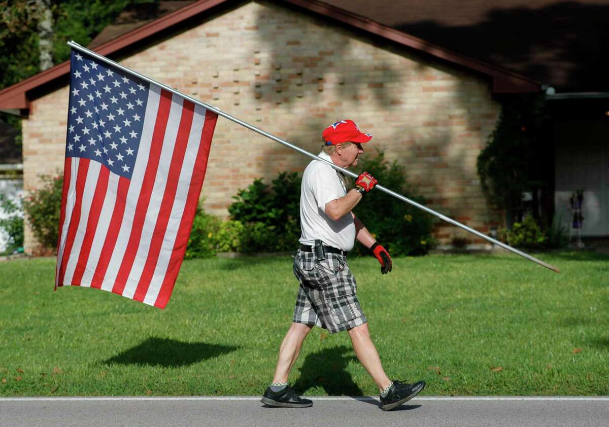 Panorama Lions Club member Bill King carries an American flag as he and his wife, Kim, install flags in front of homes for the Labor Day weekend, Saturday, Sept. 4, 2021, in Panorama. The club’s program, which places flags outside of people’s homes six days a year, raises $20,000 that the club then uses in various charitable community projects.