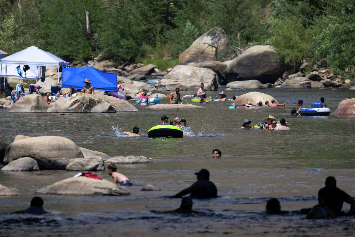 People cool off in the Kern River, which has been running at a fraction of its capacity toward the giant reservoir Lake Isabella, itself at 8% of capacity.