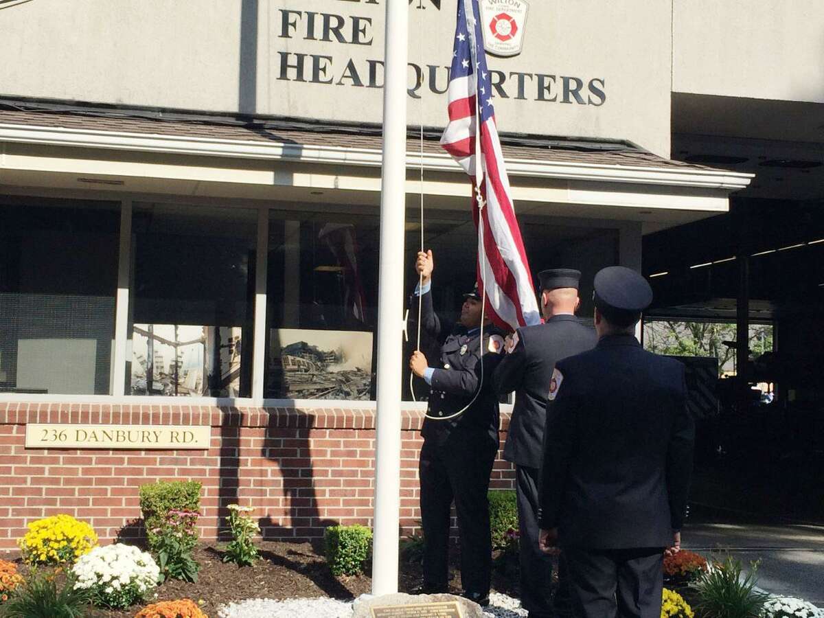 Firefighters raise the American flag to half staff at Wilton’s 9/11 remembrance ceremony in 2019.