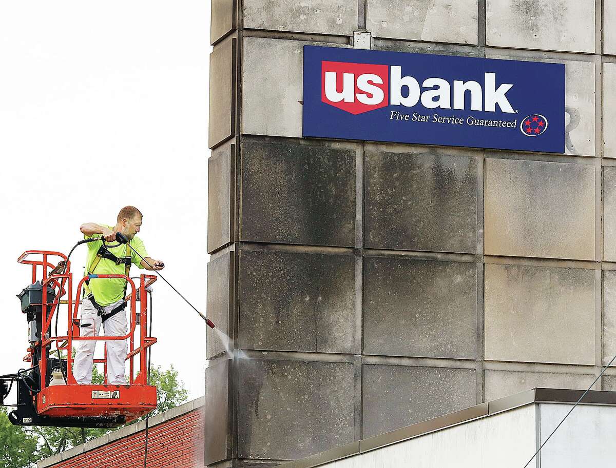 John Badman|The Telegraph A worker uses a power washer Friday to clean the concrete portion of the Alton branch of US Bank at 1520 Washinton Ave. in Alton. Environmental pollution is part of the reason the concrete stains dark.