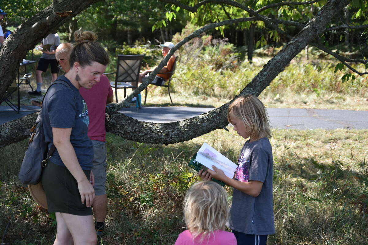 Emily and Ella Vandermolen stand by as Gavin Vandermolen looks up what type of snake the family had just seen at North Point Park in Onekama during the Bioblitz event on Friday. 