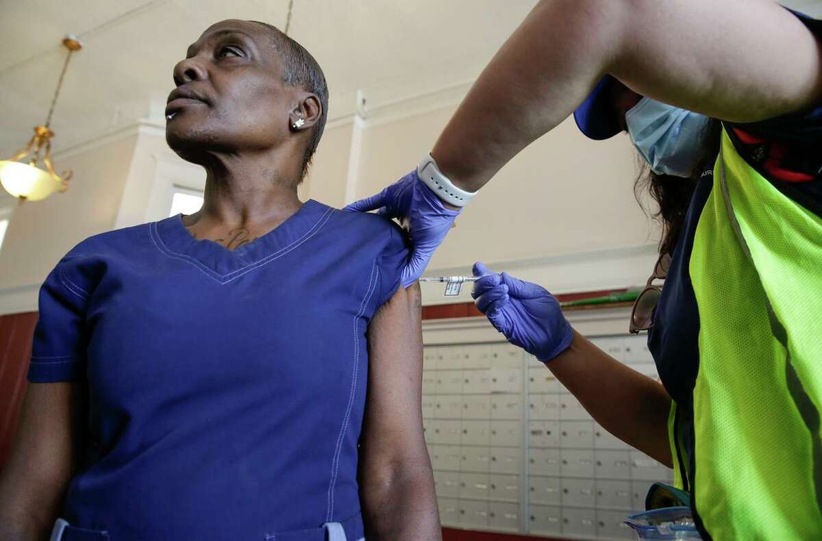 A UCSF nurse delivers a coronavirus vaccine booster on Aug. 18 to a patient in San Francisco’s Tenderloin district as part of a community medical outreach program. Redesigned boosters approved last week target the omicron variant and could help prevent another COVID surge this fall and winter.