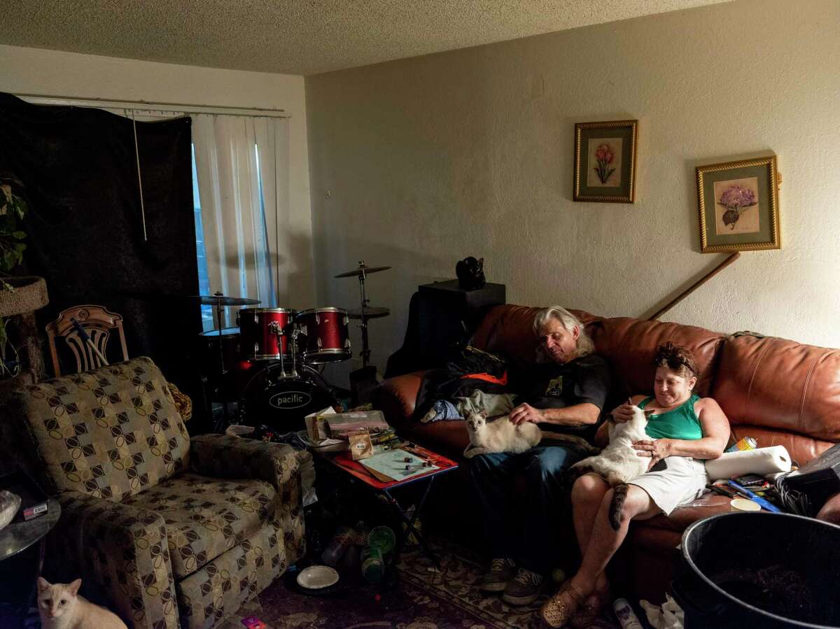 Earnest Hawkins, 74, and his wife, Elaine Glover-Harrington, 50, play with their cats inside their apartment during a heat wave in Antioch.