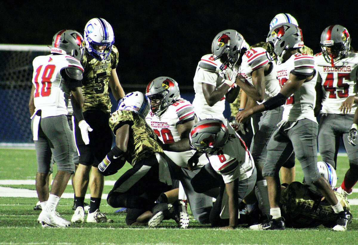 Alton players surround a Blue Devils running back after he picks up yardage Friday at Flinn Stadium in Quincy.