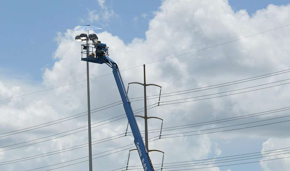 A worker replaces a light bulb in the parking lot of NRG on Monday, Aug. 1, 2022 in Houston.