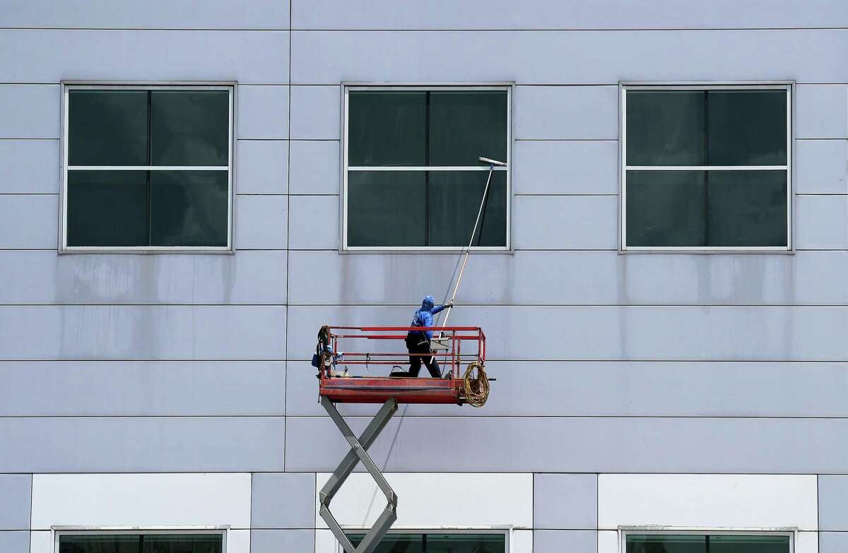 A worker cleans off the window on the second floor of NRG Center on Sunday, July 31, 2022 in Houston.
