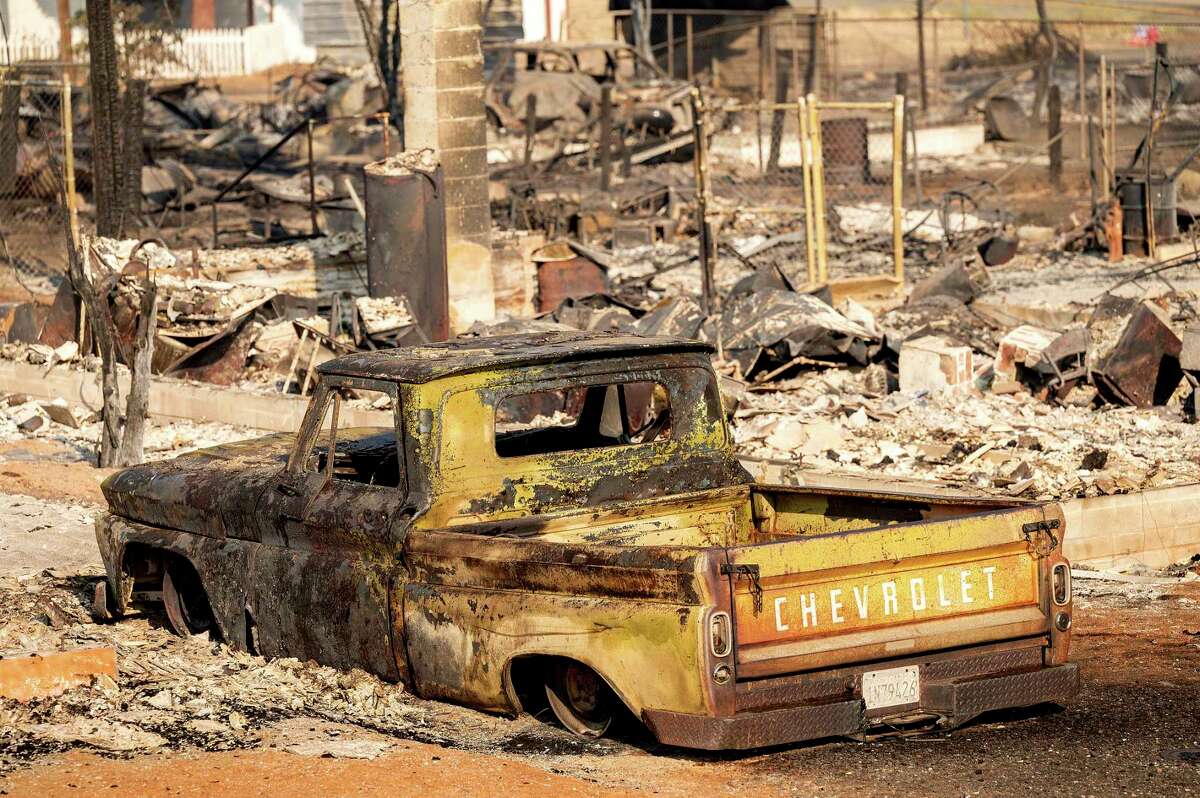 A scorched pickup truck sits in front of a Wakefield Avenue home destroyed by the Mill Fire on Saturday, Sept. 3, 2022, in Weed, Calif.