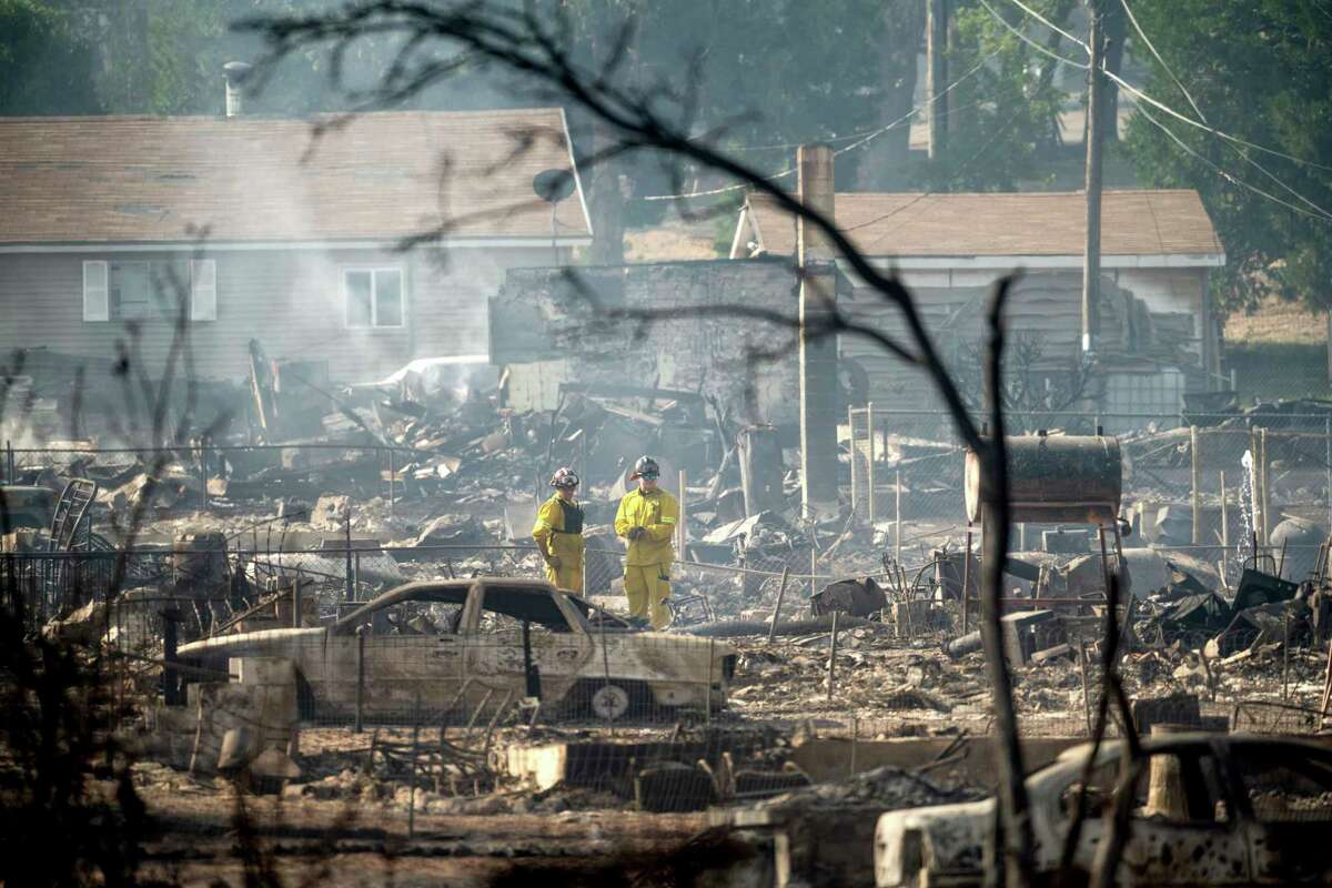Firefighters survey homes on Wakefield Avenue destroyed by the Mill Fire on Saturday, Sept. 3, 2022, in Weed, Calif.