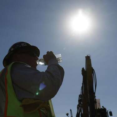 2022年9月1日，星期四，在加利福尼亚州安提俄克的菲兹仁路，弗雷斯诺的建筑工人蒂姆·罗森菲尔德在酷热中工作时喝着冷水。