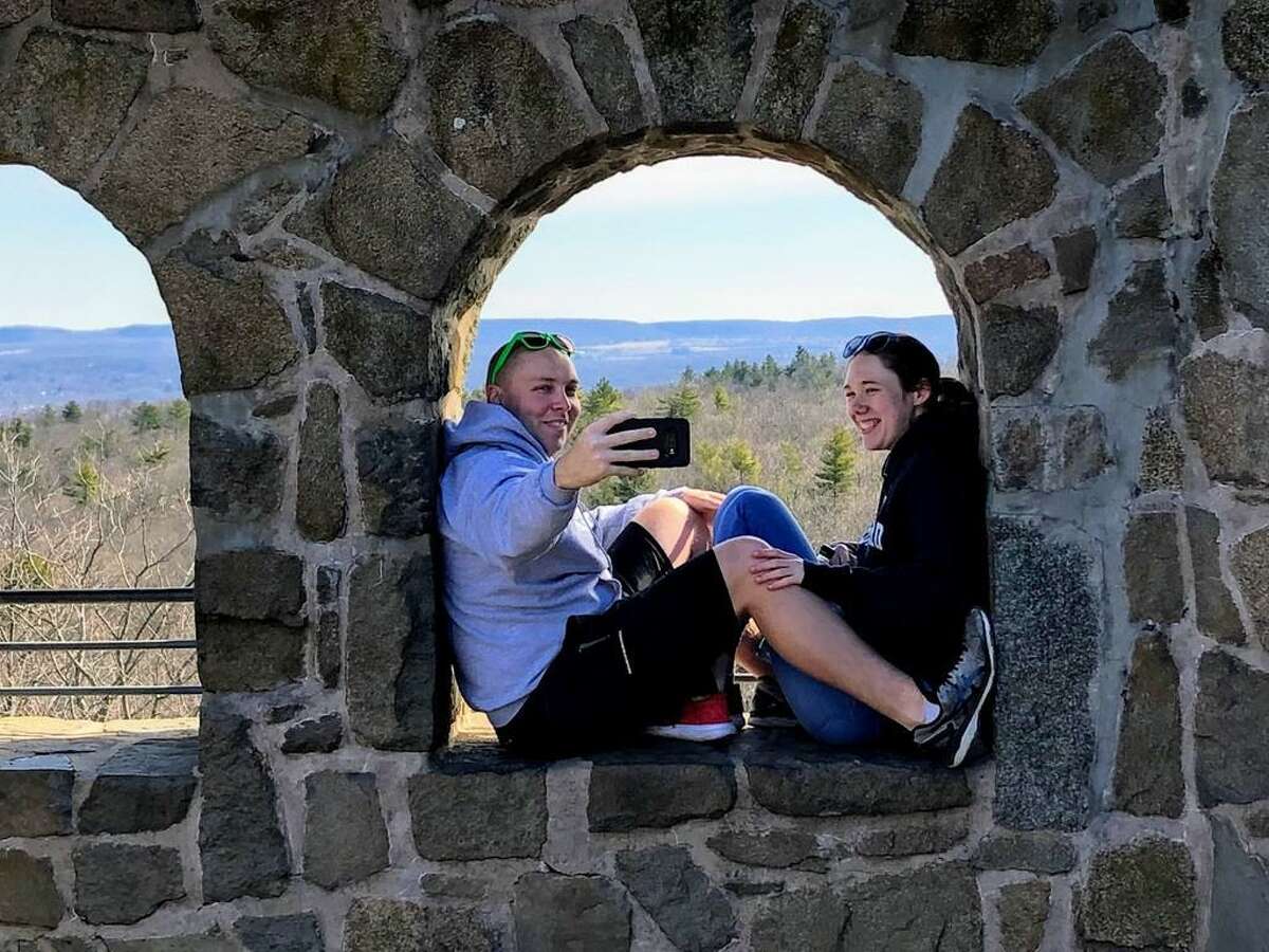 Two people enjoy a photo on the castle at the top of Sleeping Giant State Park, which closed Saturday because its parking lot was full.