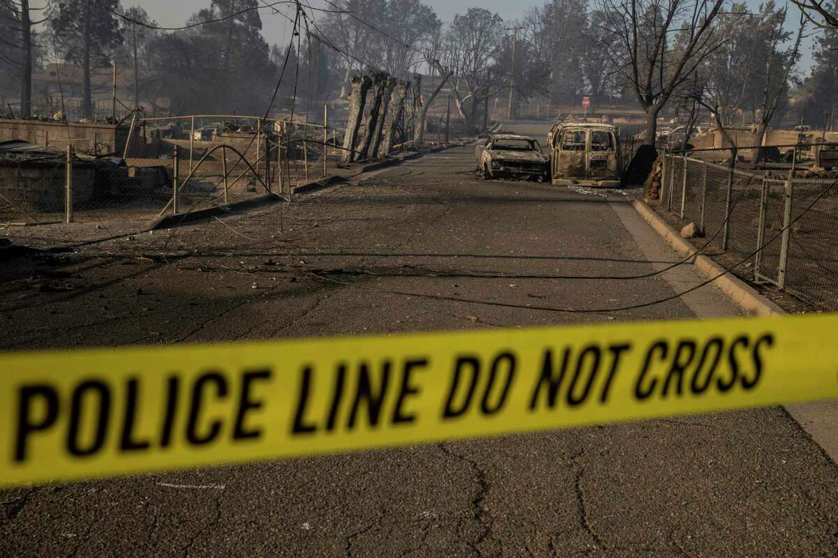 A police cordon is seen across a road in the Lincoln Heights neighborhood during the Mill Fire in Weed, Calif. Saturday, Sept. 3, 2022.