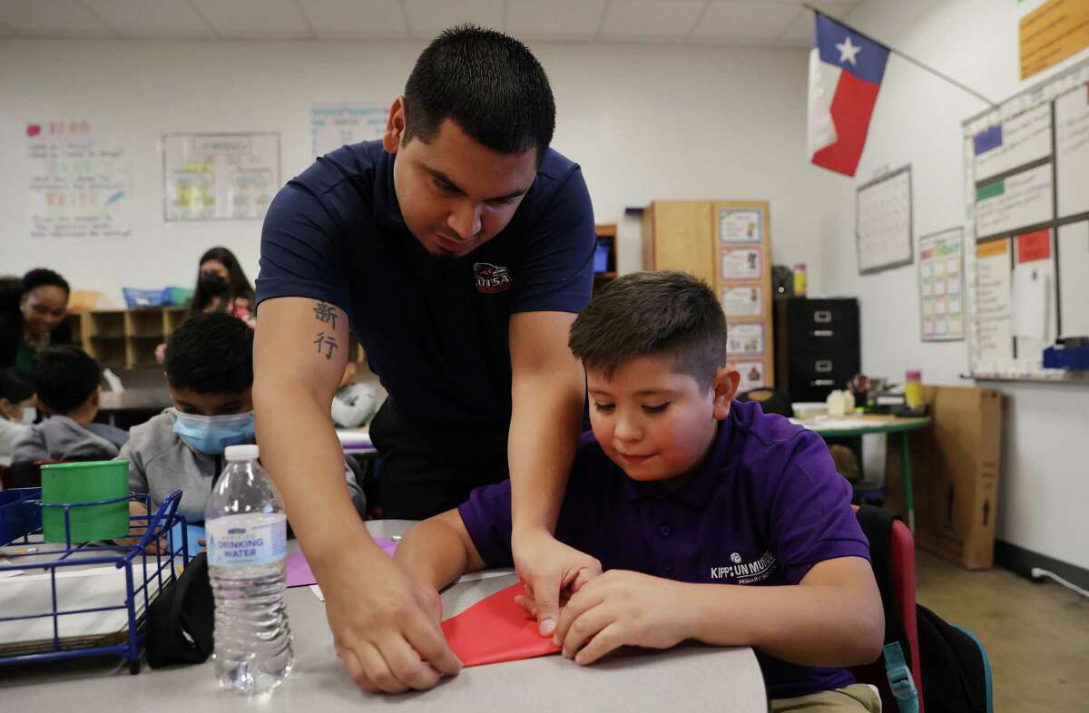 Science teacher Luis Arreola helps his student, Jose Contreras, fold a paper plane during an exercise Aug. 22. Charter schools like KIPP Un Mundo compete with traditional school districts for students and get rated by the state the same way.
