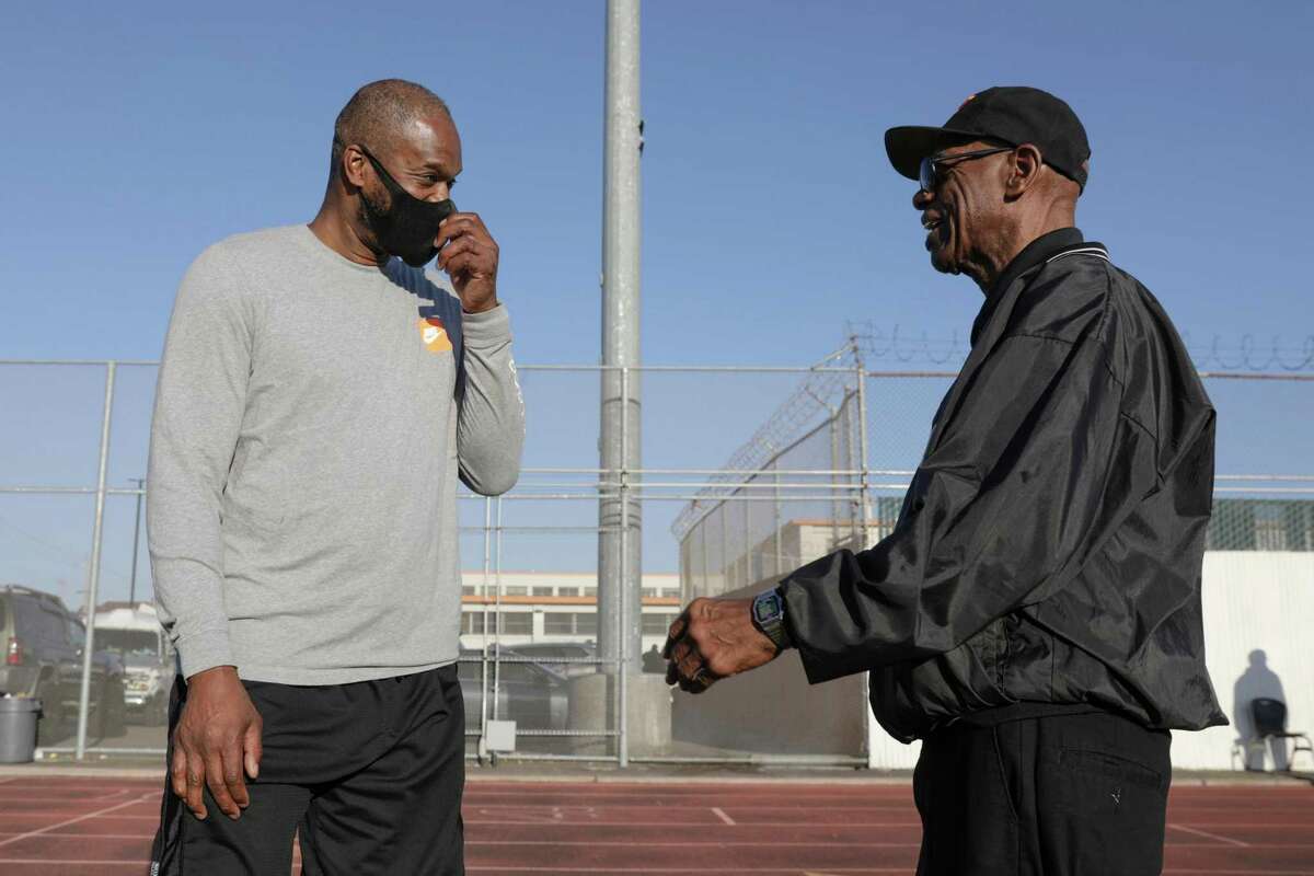 McClymonds High School alum Antonio Davis, left, chats with coach emeritus Ralph Belamy, right, before a ceremony to honor basketball Hall of Famer Bill Russell (the school's most famous alum) before Friday night's football game vs. Bellarmine at McClymonds High School in Oakland, Calif. on Friday, September 2, 2022.