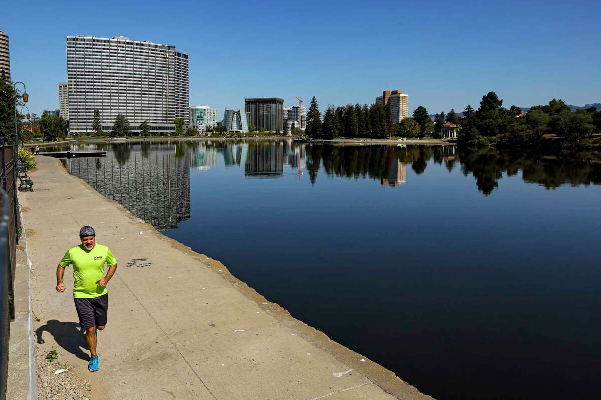 A person jogs under noon rays at Lake Merritt in Oakland on Monday. Heat warnings and advisories have been extended until Thursday.