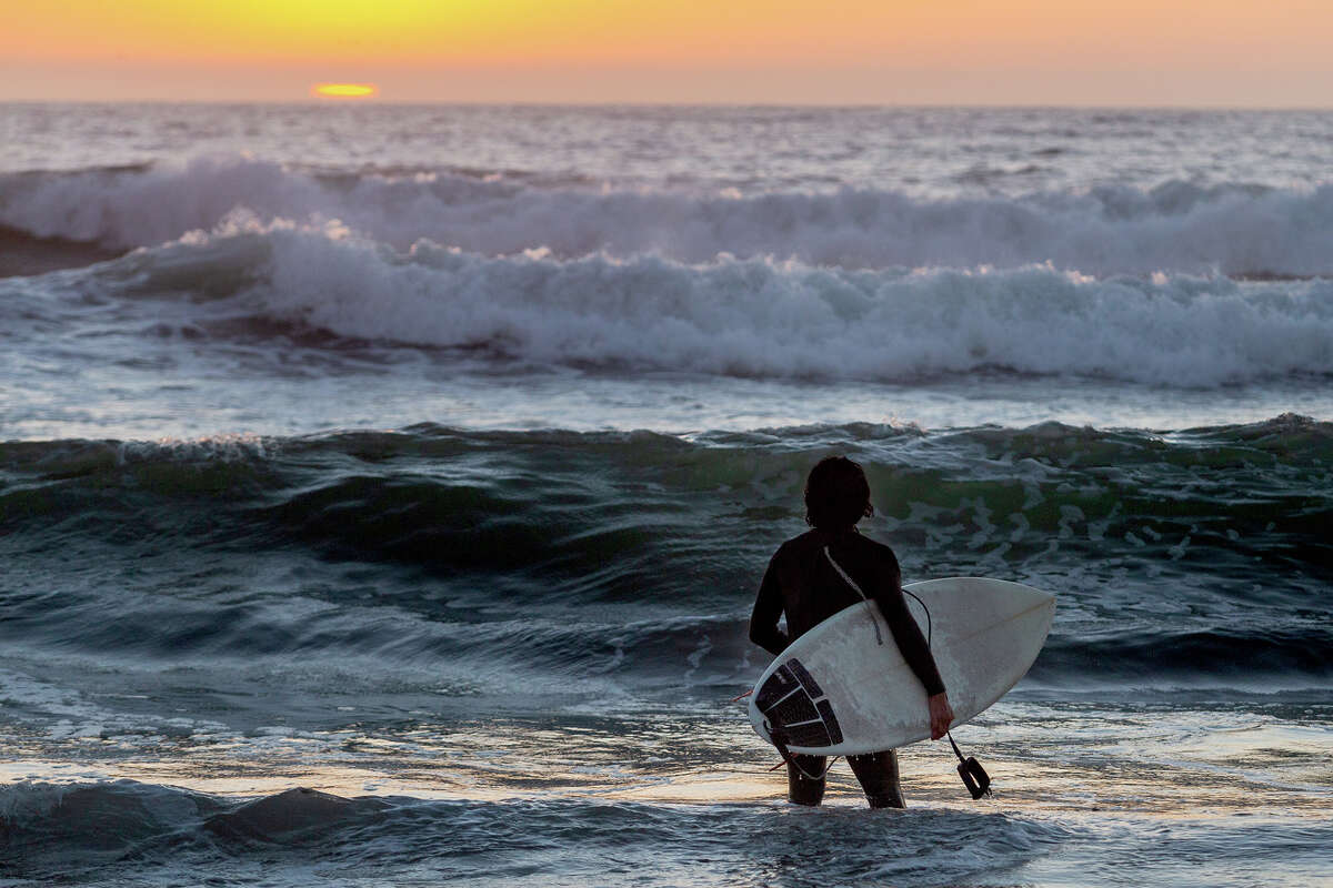 Surfer Mark Paiz catches the setting sun during a late day session at San Francisco's Ocean Beach, on Sunday evening, Sept. 4, 2022.