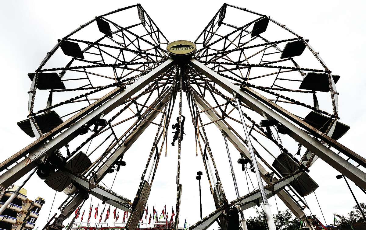 John Badman|The Telegraph A Luehrs' Ideal Rides employee, using a safety harness, hangs from a center section of a ride, helping with the set-up and expansion of the Luehrs' ferris wheel's sections.