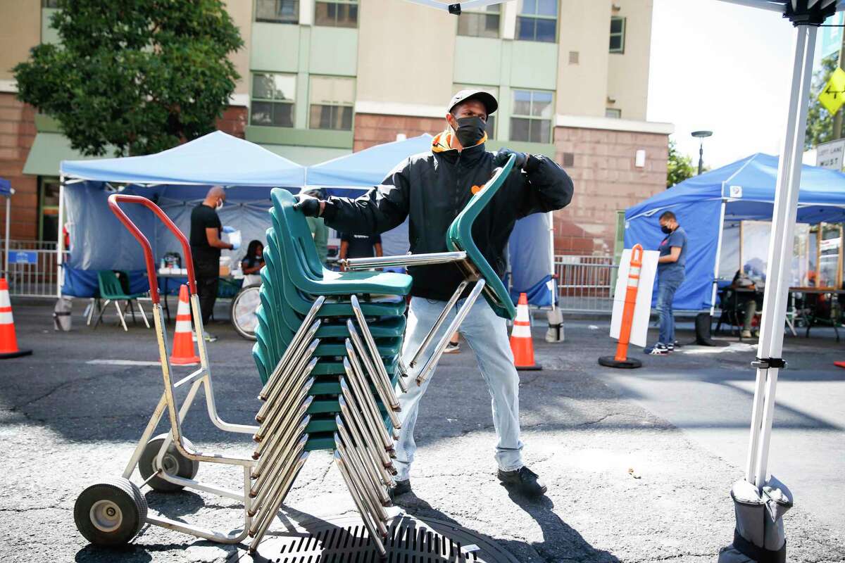 Khusar Mobley, community safety monitor, stacks and moves chairs as he works in the sun to set up for Glide’s Daily Free Meal program on Tuesday, September 6, 2022 in San Francisco, Calif.