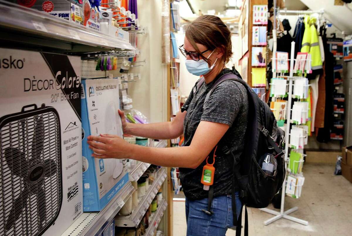 Brenna Alexander looks on at fans while contemplating shopping at Cole Hardware in San Francisco on Tuesday.  Some homes in San Francisco have air conditioning.