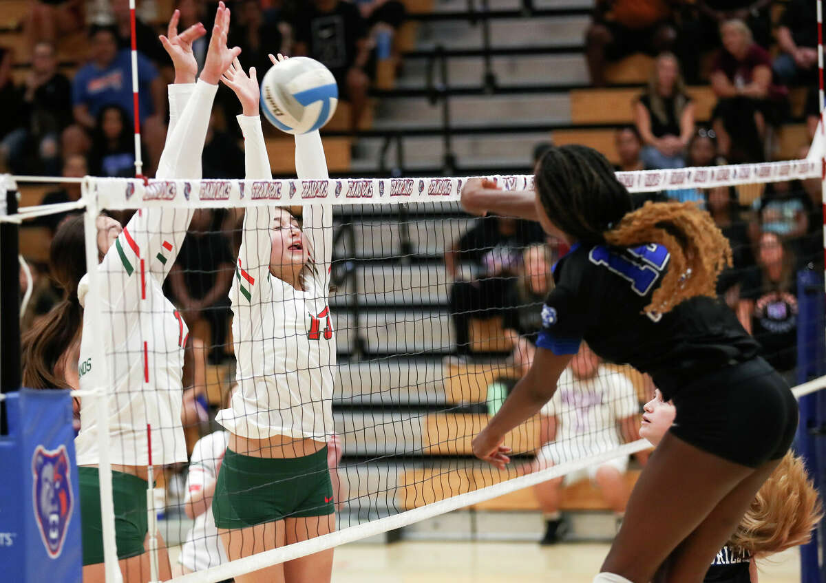 The Woodlands' Claire DeWine (17) and Mariana Tovar (13) block a shot by Grand Oaks' Samara Coleman (12) in the third set of a District 13-6A high school volleyball match at Grand Oaks High School, Tuesday, Sept. 6, 2022, in Spring.
