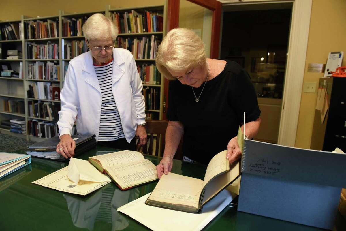 Alice Flynn, left, and JoAnn Fitzgerald, right, the former, and current Ilium Literary Club presidents, look over club records stored at the Hart Cluett Museum on Wednesday, Sept. 7, 2022, in Troy, N.Y. The women's reading group has ben part of the Troy club and arts scene since 1922.