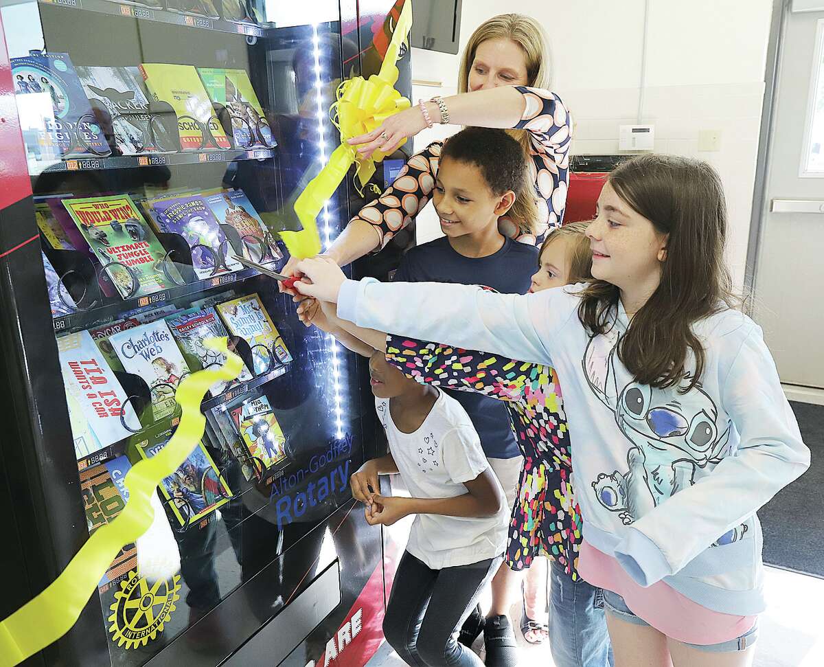 John Badman|The Telegraph North Elementary School Principal Heather Johnson, top, helps students cut the ribbon on the school's new book vending machine made possible by the Alton-Godfrey Rotary Club.
