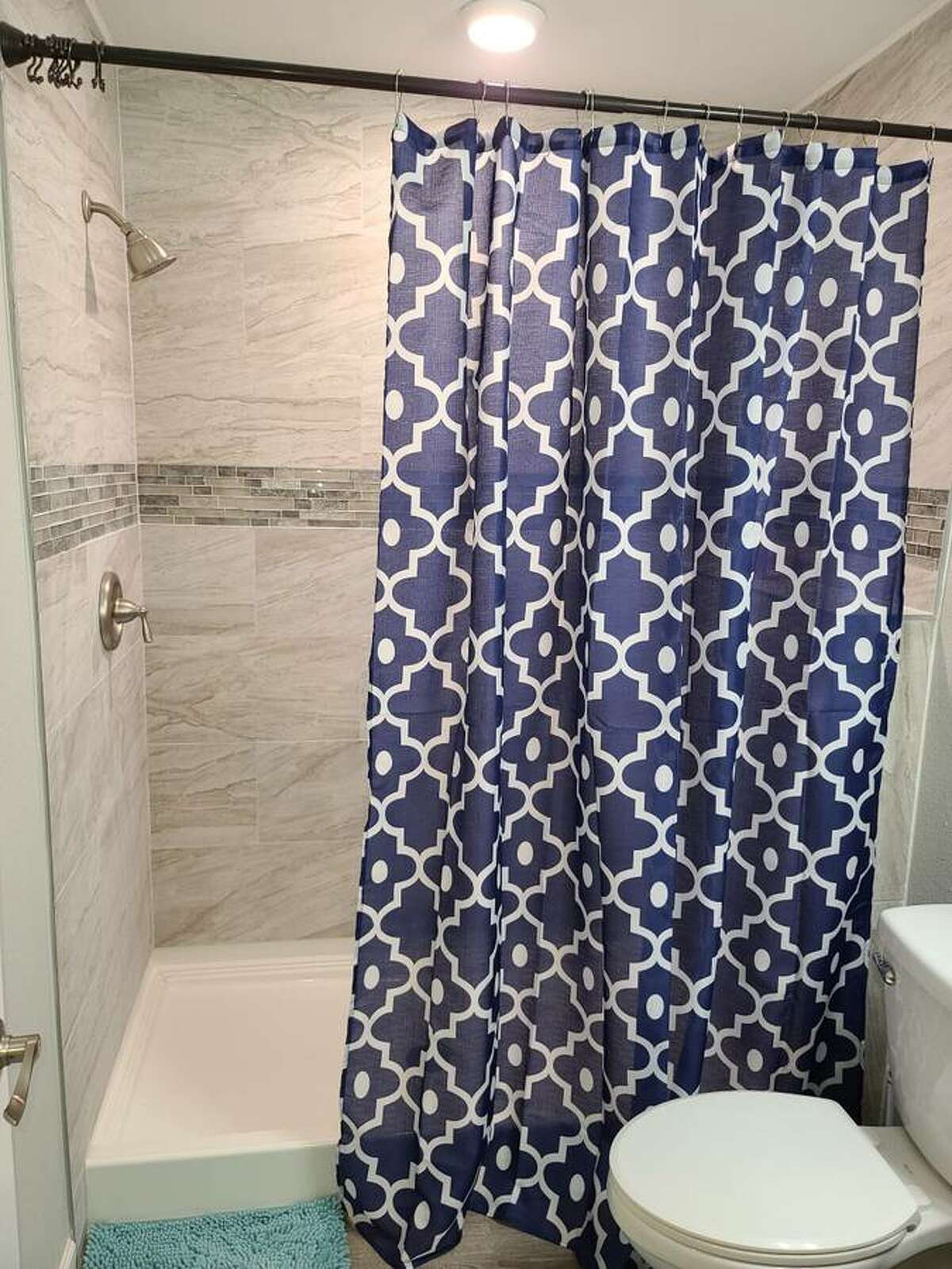 The bathroom has a walk-in shower lined with granite tiles.