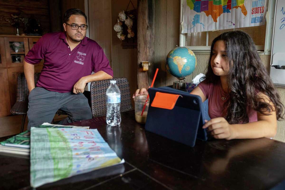Adam Martinez, left, sits in his home Tuesday with his daughter Analiya on the first day of school for Uvalde CISD. Martinez’s two school-aged children are doing virtual school because he doesn’t feel safe sending them back to campus following the mass shooting at Robb Elementary School in Uvalde in May that killed 19 children and two teachers.