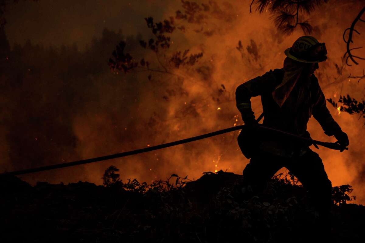 A firefighter with the Cal Fire Santa Clara Unit drags a hose while battling the Mosquito Fire near Michigan Bluff in unincorporated Placer County, Calif. Wednesday, Sept. 7, 2022.