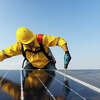 STOCK IMAGE Solar panel technician with drill installing solar panels on roof