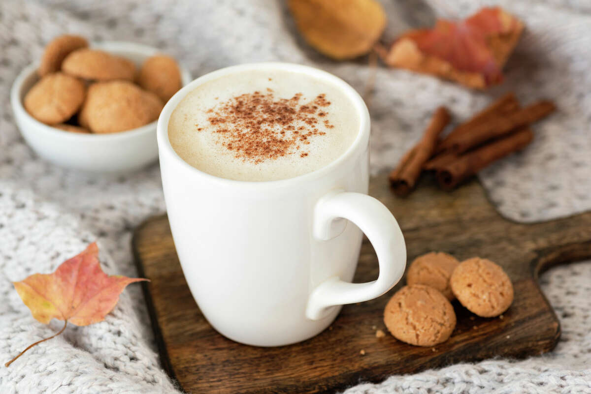 Pumpkin spice latte or cappucino and cookies on wooden serving tray. Autumn comfort food, warm coffee with milk foam in white cup
